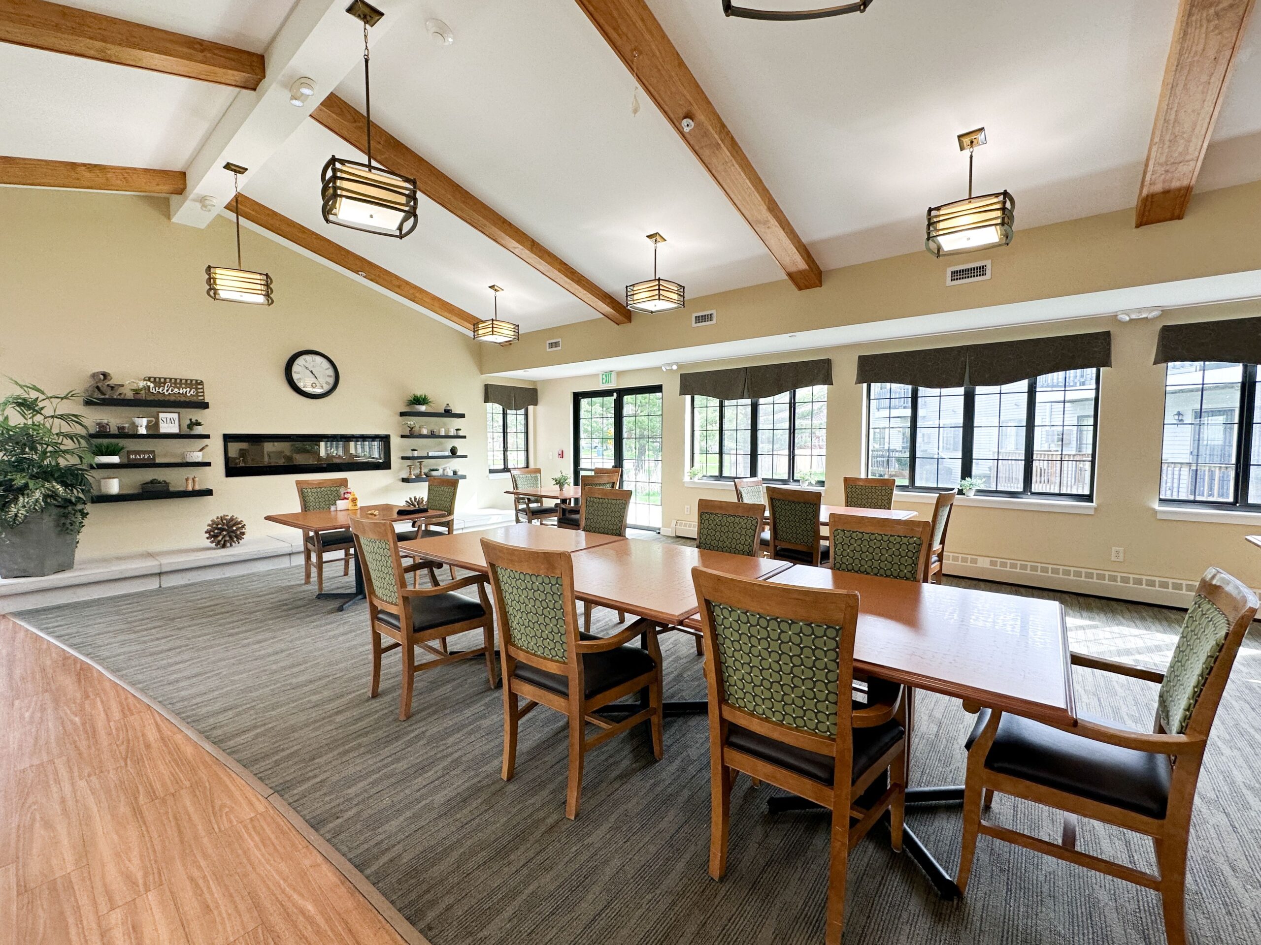Multiple tables with seating next to large windows, and vaulted ceilings